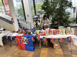 Stand de produits et exposantes, décoré de drapeaux haïtiens, à la Journée Cultures solidaires.